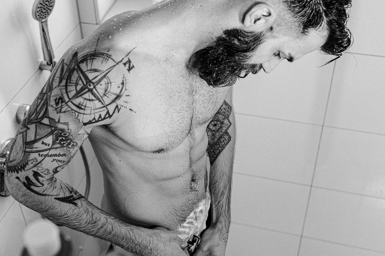 Mann in der Dusche rasiert sich im Intimbereich.