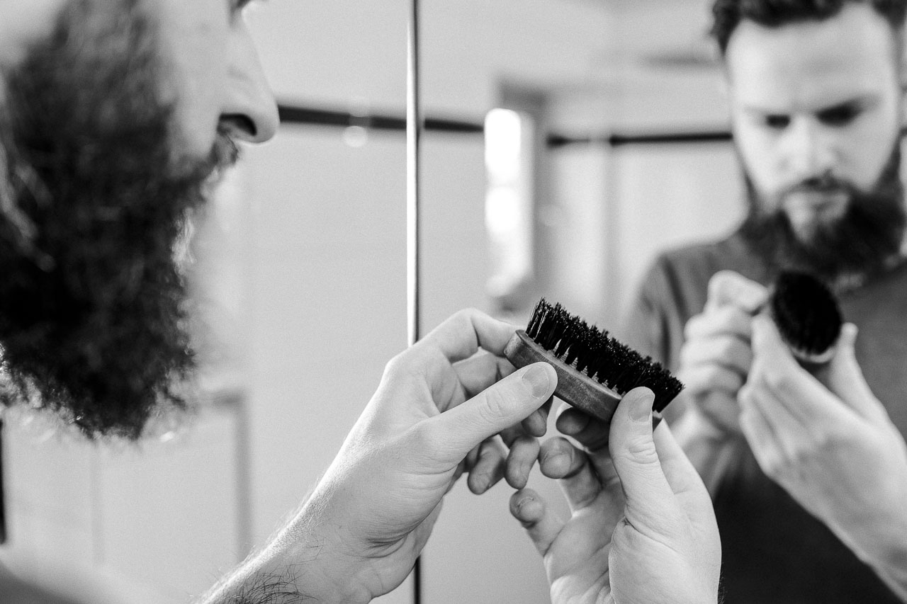 Mann mit Bart begutachtet eine Bartbürste.